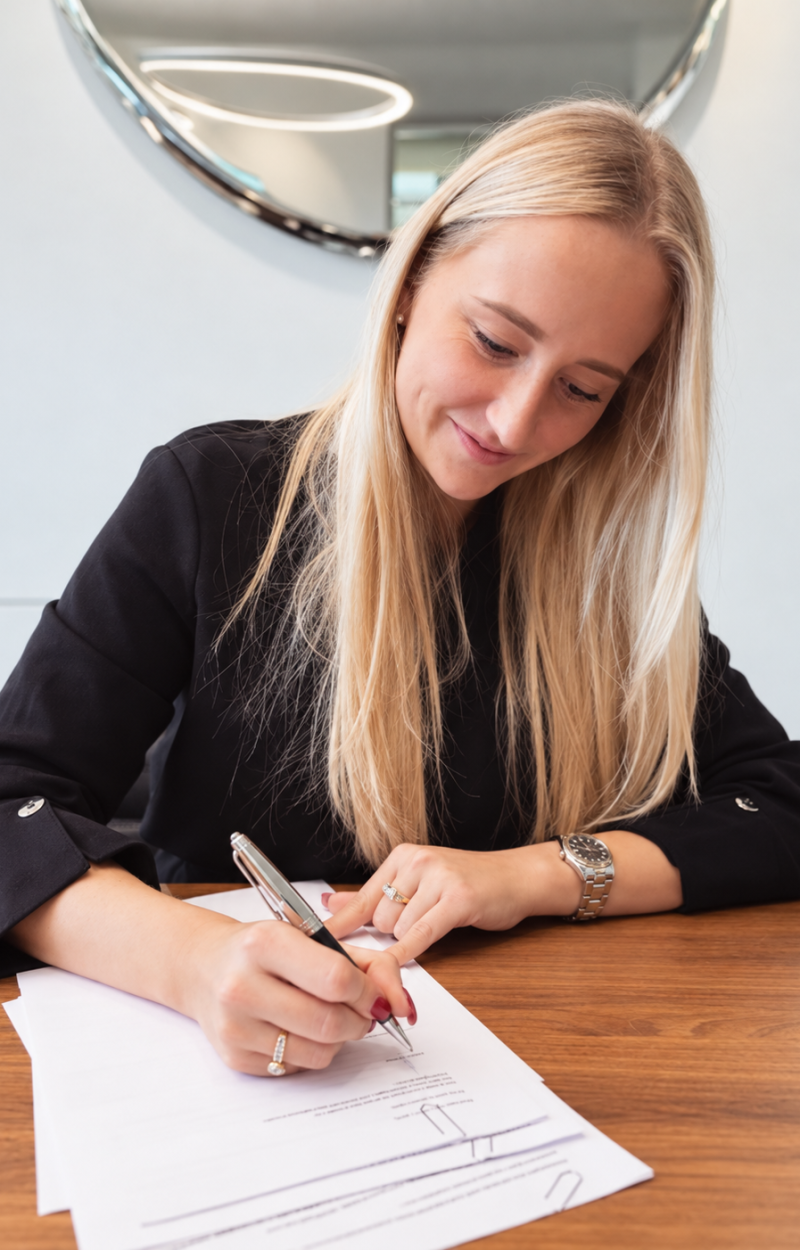 Blonde Frau unterschreibt Vertrag am Schreibtisch